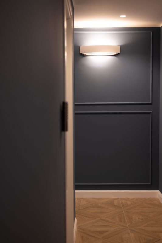 Disimpegno con boiserie blu e applique a parete accesa