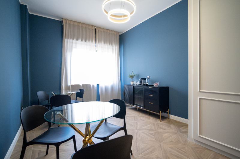 Sala colazione con tavoli in vetro e pareti blu petrolio
