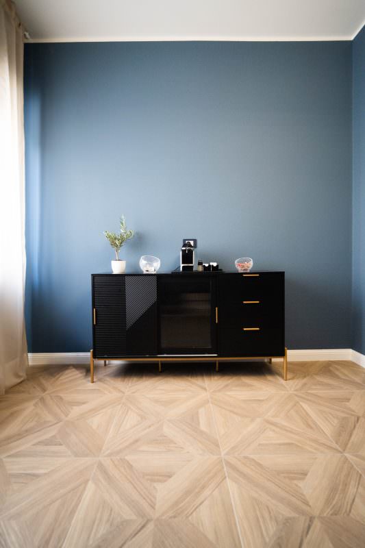 Credenza nera con macchina da caffè e pianta di olivo su parete blu