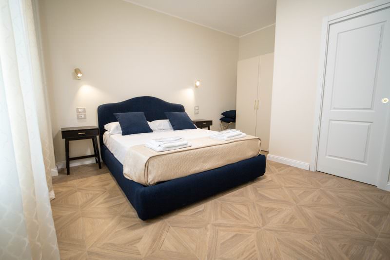 Camera matrimoniale con letto blu notte e parquet a intarsio