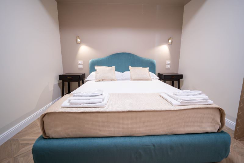 Letto matrimoniale con testiera in velluto turchese