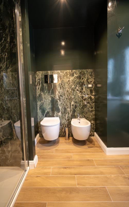 Bagno con rivestimento in marmo verde e box doccia