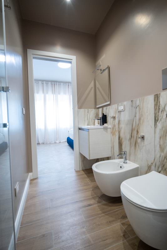 Bagno in marmo chiaro con affaccio sulla camera da letto